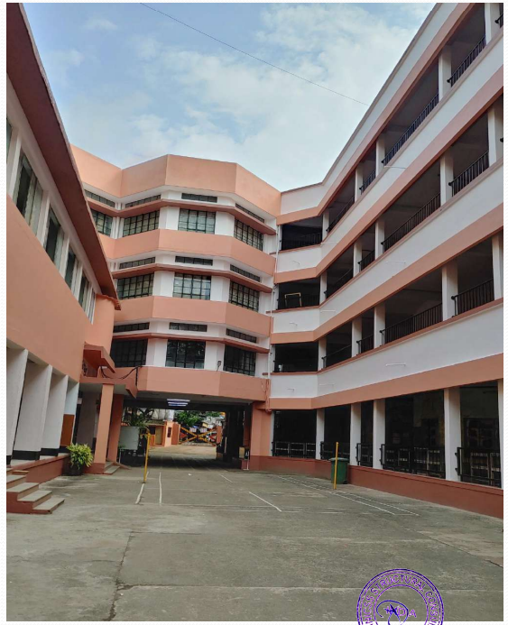 Open courtyard of a multi-story building with peach and white exterior walls and multiple windows under a partly cloudy sky.
