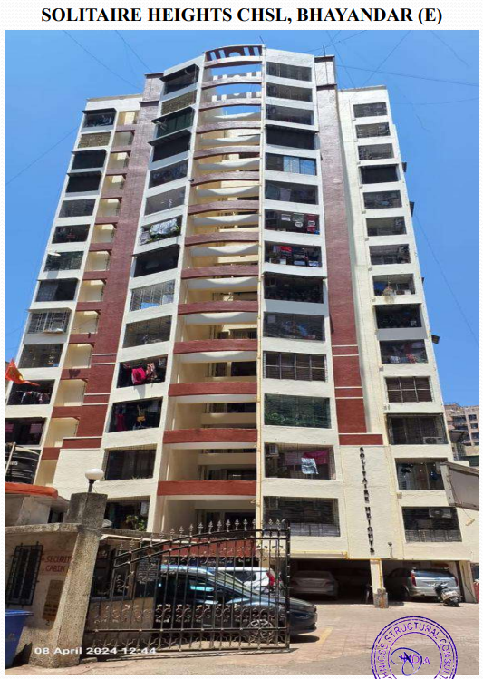 Multi-story residential building Solitaire Heights CHSL in Bhayandar (E) under clear blue sky with gated entrance and parked cars.